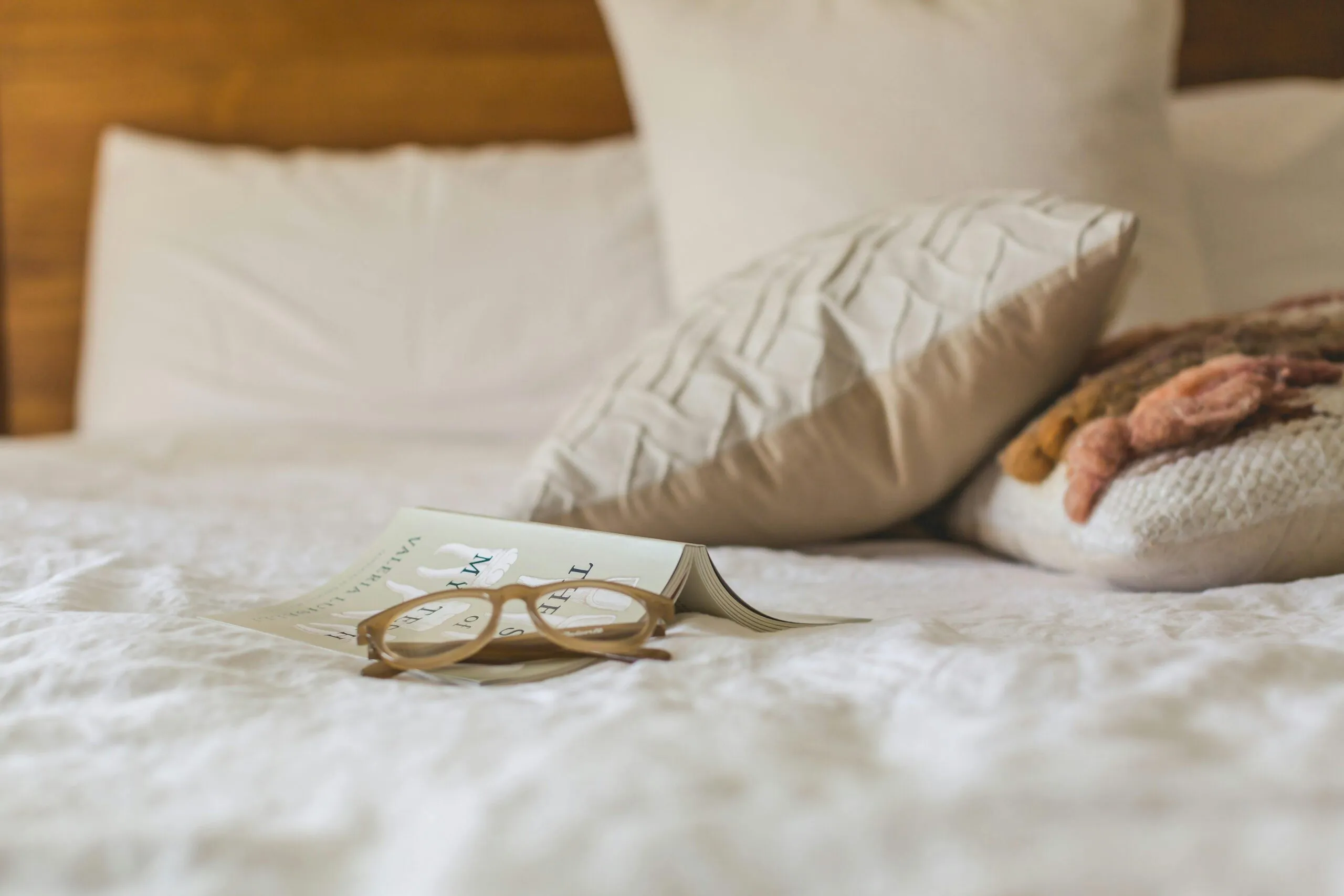 Kussens met een open boek en leesbril op bed
