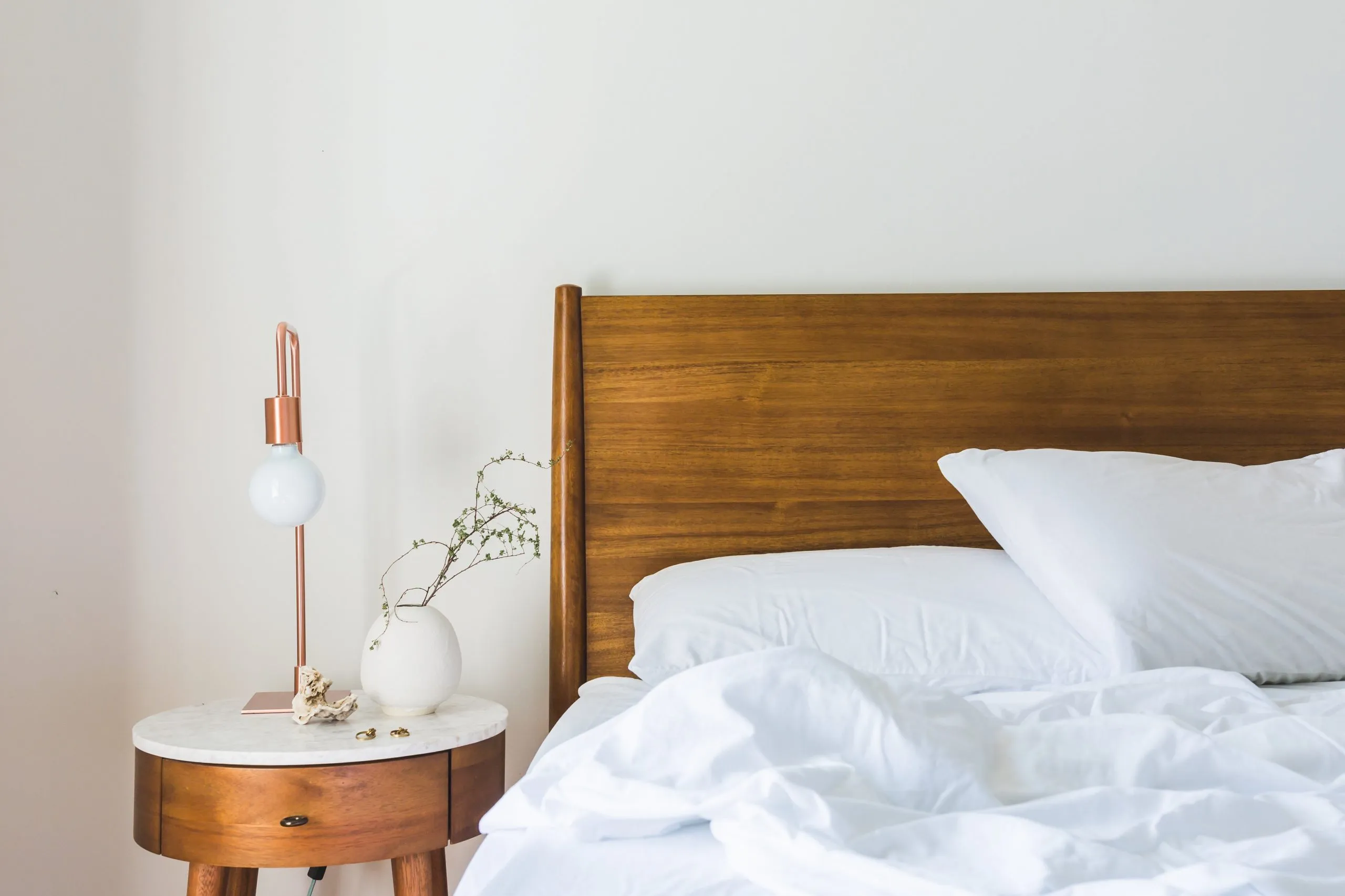 Opgemaakt bed met wit beddengoed in een lichte slaapkamer
